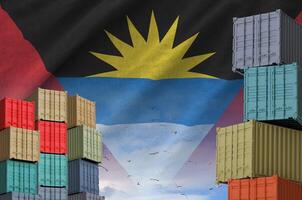 Antigua and Barbuda flag and big stack of shipping cargo containers in docks with sky background photo