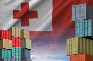 Tonga flag and big stack of shipping cargo containers in docks with sky background photo