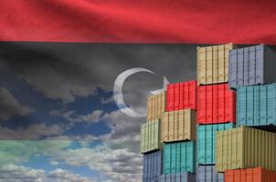 Libya flag and big stack of shipping cargo containers in docks with sky background photo