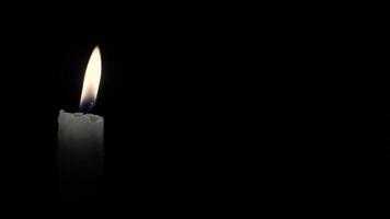 Candle. Seamlessly loop footage with copy space. Burning candle isolated on a black background. Infinitely flame of a white candle in the night. video