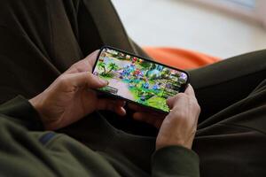 Fantasy Westward Journey mobile iOS game on iPhone 15 smartphone screen in male hands during mobile gameplay photo