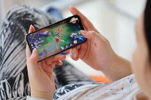 Honor of Kings mobile iOS game on iPhone 15 smartphone screen in female hands during mobile gameplay photo