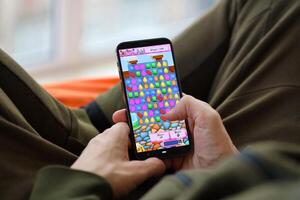 Candy Crush Saga mobile iOS game on iPhone 15 smartphone screen in male hands during mobile gameplay photo