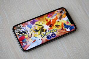 Pokemon GO mobile iOS game on iPhone 15 smartphone screen on wooden table during mobile gameplay photo