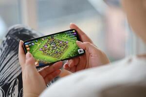 Clash of Clans mobile iOS game on iPhone 15 smartphone screen in female hands during mobile gameplay photo