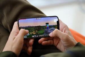 Minecraft mobile iOS game on iPhone 15 smartphone screen in male hands during mobile gameplay photo