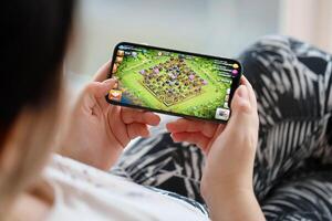 Clash of Clans mobile iOS game on iPhone 15 smartphone screen in female hands during mobile gameplay photo