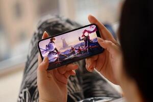 Honor of Kings mobile iOS game on iPhone 15 smartphone screen in female hands during mobile gameplay photo