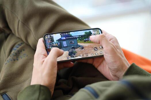 PUBG PlayerUnknowns Battlegrounds mobile iOS game on iPhone 15 smartphone screen in male hands during mobile gameplay photo
