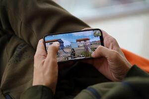 PUBG PlayerUnknowns Battlegrounds mobile iOS game on iPhone 15 smartphone screen in male hands during mobile gameplay photo