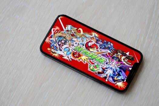 Monster Strike mobile iOS game on iPhone 15 smartphone screen on wooden table during mobile gameplay photo