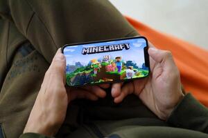 Minecraft mobile iOS game on iPhone 15 smartphone screen in male hands during mobile gameplay photo