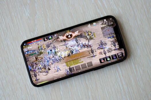Lineage M mobile iOS game on iPhone 15 smartphone screen on wooden table during mobile gameplay photo