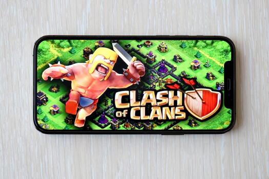 Clash of Clans mobile iOS game on iPhone 15 smartphone screen on wooden table during mobile gameplay photo