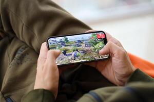 PUBG PlayerUnknowns Battlegrounds mobile iOS game on iPhone 15 smartphone screen in male hands during mobile gameplay photo