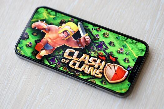 Clash of Clans mobile iOS game on iPhone 15 smartphone screen on wooden table during mobile gameplay photo
