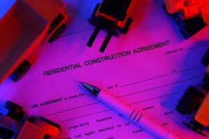 Residential construction agreement with pen lies on table with many yellow construction and service toy vehicles photo