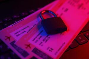 Fictional air tickets and small padlock on computer keyboard photo