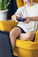 The woman is holding a black jostic, joystick, navigation key, cursor buttons, navigation control. She plays the game on the console. vertical photo