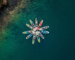 aerial view of a group of paddleboarders forming a star pattern on the clear blue waters photo