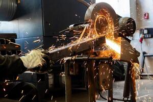 The man is cutting a metal box using cutting machine and the fire sparks splashes outside photo