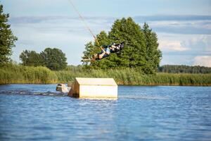 Young man wakeboarding on a lake, making raley, frontroll and jumping the kickers and sliders Wakeboard photo