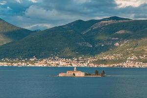 secluded monastery island against a mountainous coastal town backdrop photo