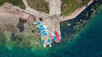 aerial view of colorful stand up paddleboards lined up on a serene beachfront photo