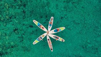 aerial view of a group of paddleboarders forming a star pattern on the clear blue waters photo