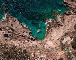 SUP paddleboards lined up on rocky shoreline with crystal clear turquoise waters photo