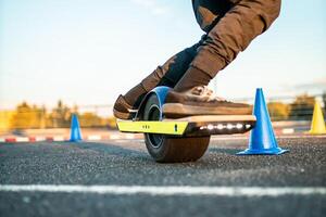 close up of a riders foot on an electric skateboard with glowing lights navigating through cones photo
