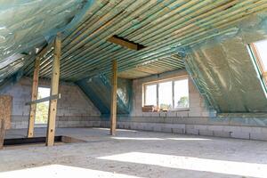 Spacious attic under construction with thermal insulation and skylights in a new home photo