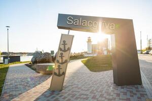 Welcoming entrance to Salacgriva in Latvia with a decorative anchor sign and lighthouse in the background photo