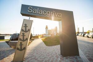 Welcoming entrance to Salacgriva in Latvia with a decorative anchor sign and lighthouse in the background photo