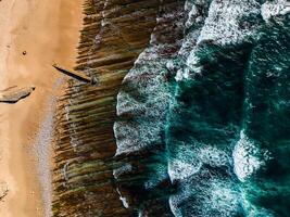 Aerial view of rocky beach with waves and clear ocean water. Drone top view photo