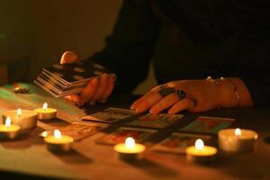 KYIV, UKRAINE - JULY 10, 2024 Tarot reader picking tarot cards. Candlelight in dark room. Tarot reader or fortune teller reading and forecasting photo
