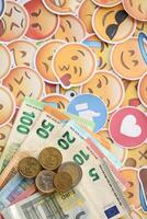 KYIV, UKRAINE - APRIL 20, 2024 European euro money and large set of stickers with Emoji yellow faces. The concept of smm, smo paid service for boost in social media photo