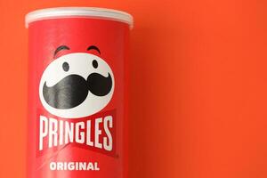 KYIV, UKRAINE - APRIL 20, 2024 Pringles original potato chips on red background. Pringles is a brand of potato snack chips photo
