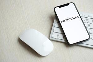 KYIV, UKRAINE - MARCH 17, 2024 Anthropic logo on iPhone display screen with apple keyboard and mouse on table photo