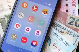 KYIV, UKRAINE - FEBRUARY 28, 2024 Dating apps icons on smartphone display and money bills photo