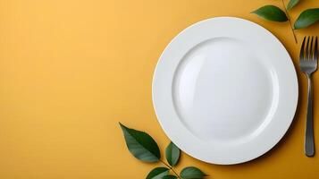 Top down view of a white plate isolated on yellow background with fork and knife with copy space photo