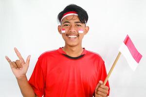 A confident young Asian man makes a number sign on an isolated white background. wearing a red shirt. Indonesian Independence day photo