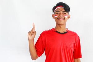 A confident young Asian man makes a number sign on an isolated white background. wearing a red shirt. Indonesian Independence day photo