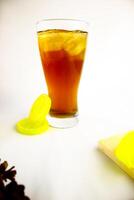 Iced tea with lemon and ice in a tall glass on a white background. The concept of a refreshing drink or lemonade on a hot summer day. Front view and copy space. photo