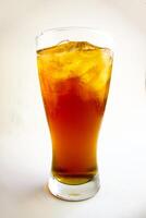 Iced tea with lemon and ice in a tall glass on a white background. The concept of a refreshing drink or lemonade on a hot summer day. Front view and copy space. photo