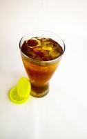 Iced tea with lemon and ice in a tall glass on a white background. The concept of a refreshing drink or lemonade on a hot summer day. Front view and copy space. photo