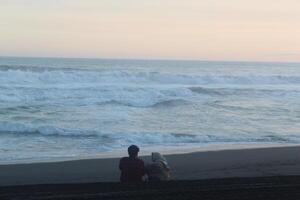 2 people were reading the Koran in the afternoon while looking at the beauty of the coast and sea photo