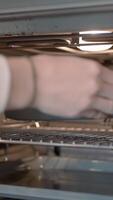 The concept of cooking. Action. A heated stove into which a frying pan with a dish is pushed. video
