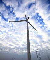 the propeller of wind turbine against the blue sky and cloudy in background photo