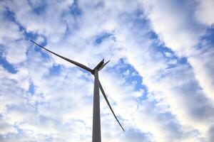 the propeller of wind turbine against the blue sky and cloudy in background photo